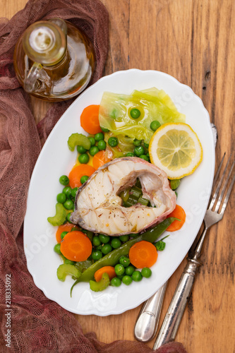 boiled fish with boiled vegetables and lemon on white dish