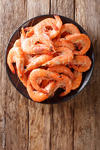 Healthy diet food: boiled wild tiger shrimps close-up on a plate on a table. vertical top view