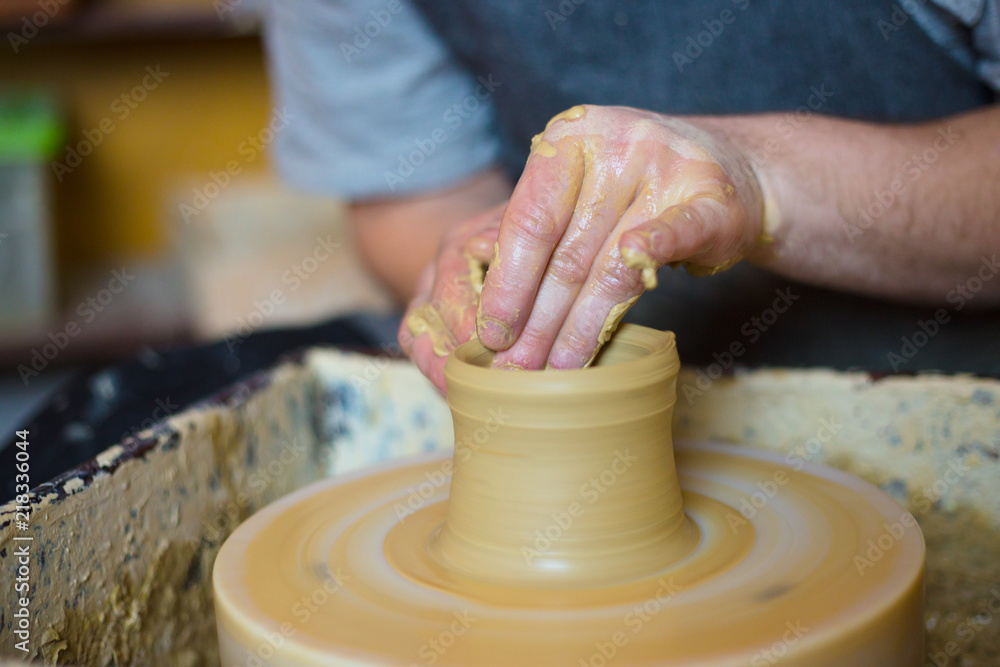 Professional male potter working with clay on potter's wheel in workshop, studio. Handmade, art and handicraft concept