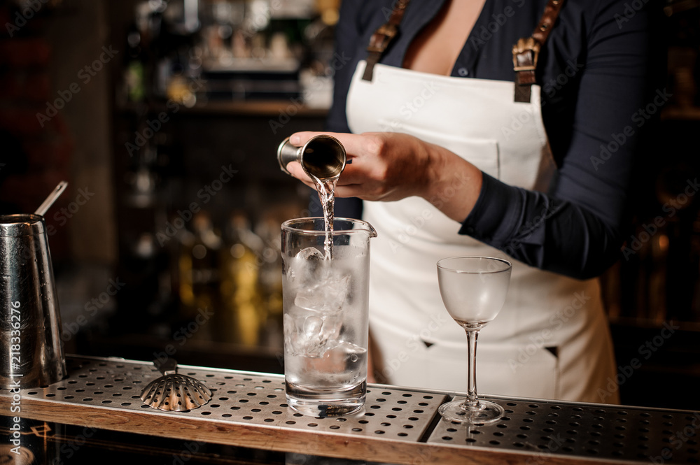 Sexy barman girl pouring vodka into a cocktail glass