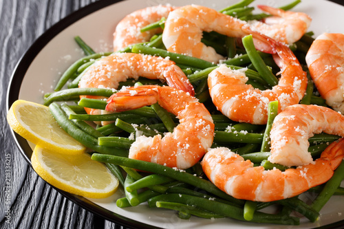 Stir fry prawns with green beans, cheese and lemon close-up on a plate. horizontal