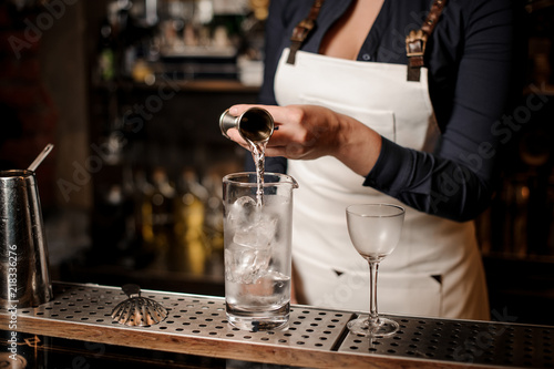 Sexy barman girl pouring vodka into a cocktail glass