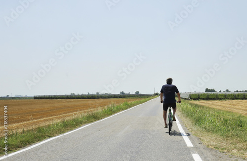Summer vacation trip on bicycle - biker ride through gold agricultural field  Bologna  Italy