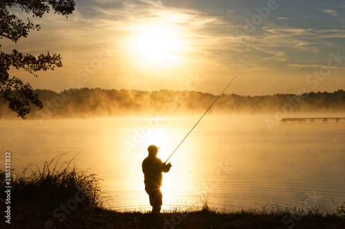 Silhouette of fisherman during foggy sunrise photo