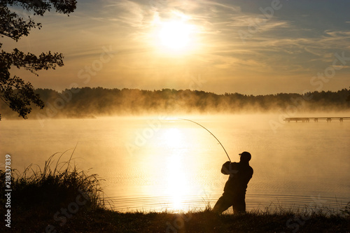 Silhouette of fisherman during foggy sunrise