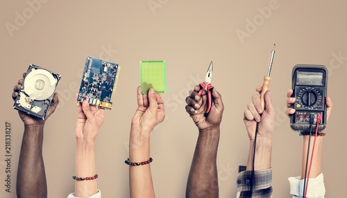 Diverse hands holding electronics tools on brown background photo