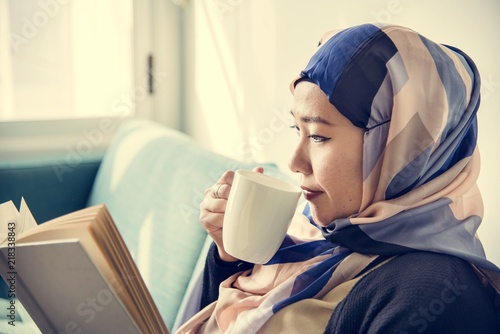 Islamic woman reading and drinking coffee