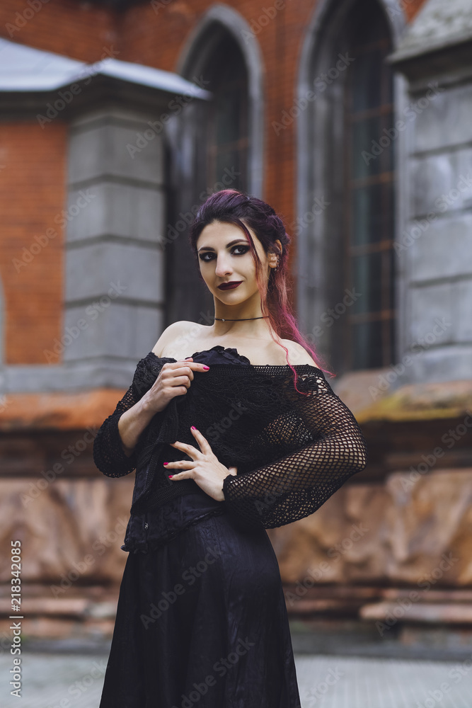 Young brunette girl in gothic style on a background architecture