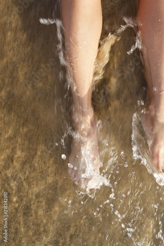 Female legs on sand washed with sea