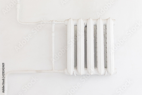 White cast iron radiator on a white wall.