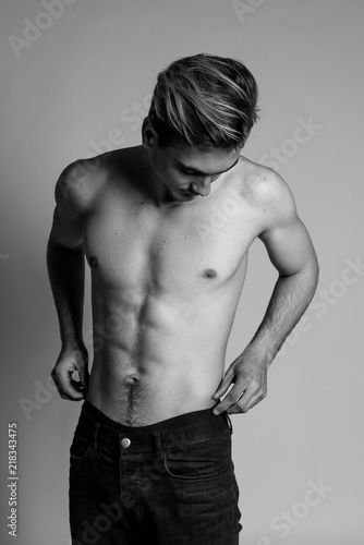 Portrait of fashion young caucasian sexy muscled attractive handsome athletic man boy model isolated on gray background