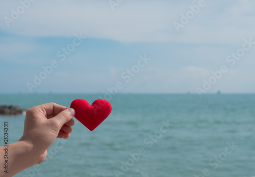 Hand with heart red shape and sea .