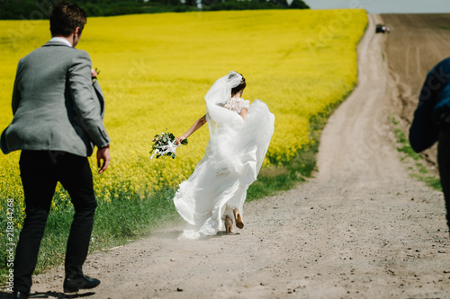 Foto Stock Bride back running away from groom on the green and yellow  field. wedding ceremony, country, outdoors. A newlywed wedding couple at  wedding day. | Adobe Stock