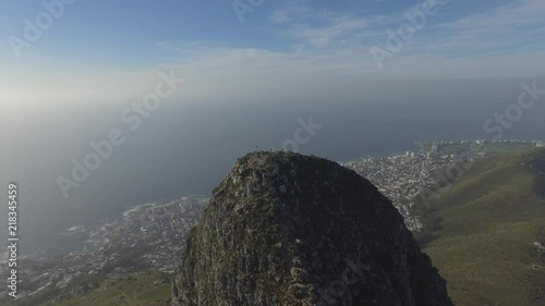 Drone shot of tourists standing on the top of Lions Head in Cape Town, with the city in the background