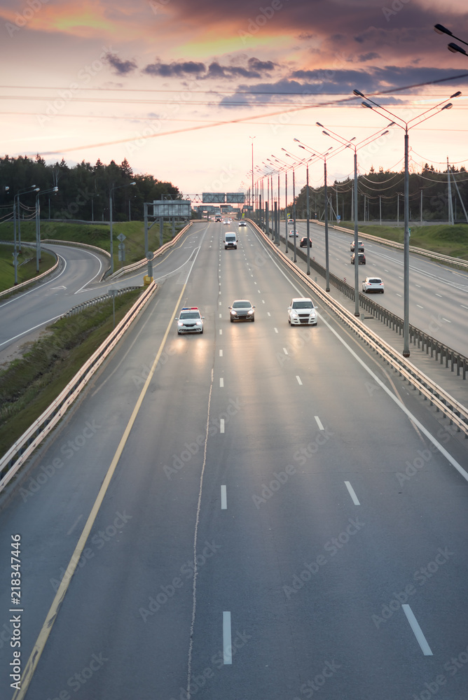 fast cars on highway in evening light. Road with metal safety barrier or rail. Sunset