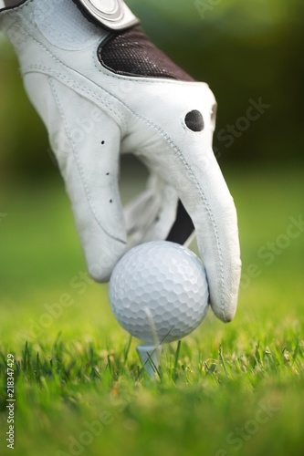 Hand with Glove Placing Golf Ball on a Tee