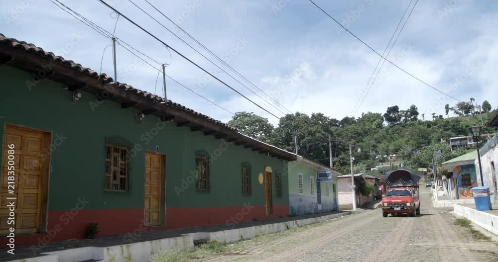 Traditional central american village house establishing shot old red pick up passing by