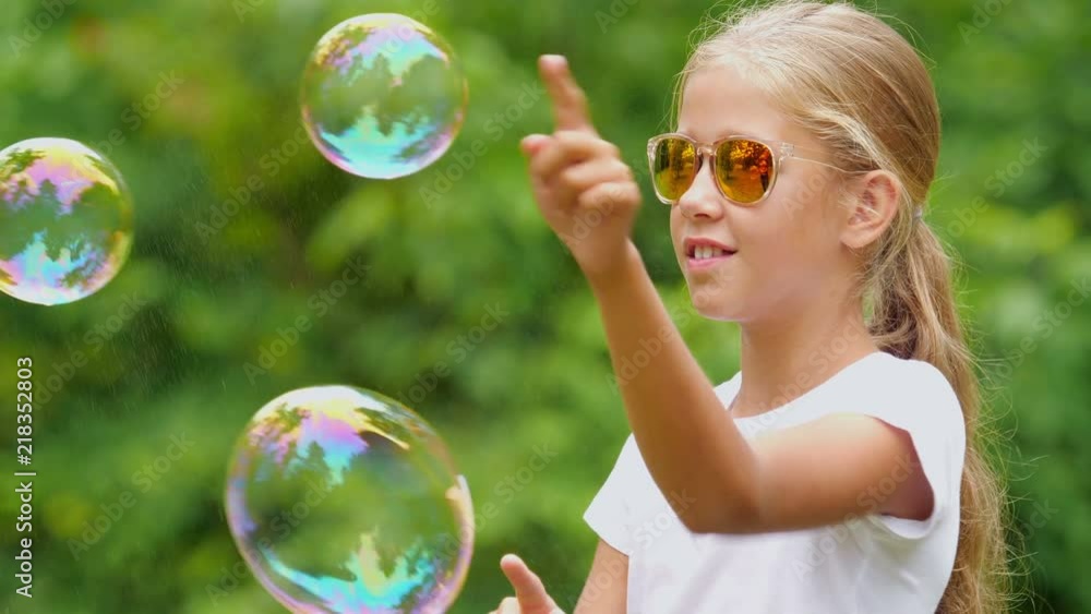 The nine-year-old girl plays with soap bubbles in the summer garden.
The nine-year-old girl plays with soap bubbles in the summer garden.