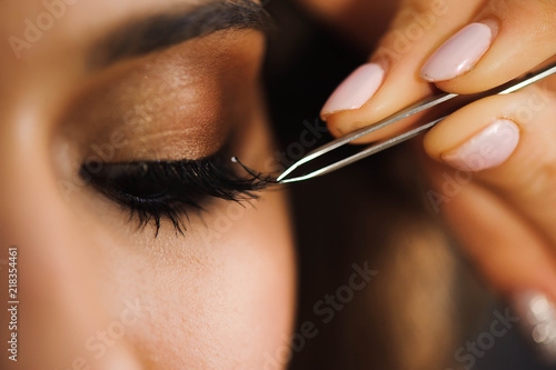 Fototapet Close up of professional stylist lengthening lashes for female client in a beauty salon