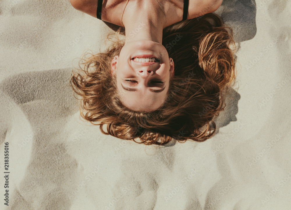 Obraz premium Close up of woman relaxing on beach sand