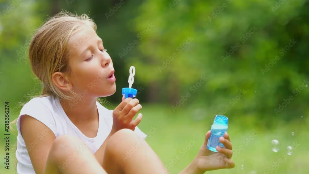 Little girl playing with soap bubbles outdoor. The nine-year-old girl plays with soap bubbles in the summer garden. Slow motion. Little girl playing with soap bubbles outdoor. The nine-year-old girl plays with soap bubbles in the summer garden. Slow motion.