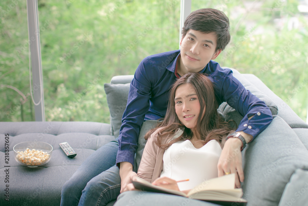 Asian teenage couple relaxing sit on sofa smiling looking at the camera happily in the luxurious room. Asian teenage couple relaxing sit on sofa smiling looking at the camera happily in the luxurious room.