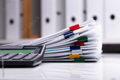 Close-up Of Calculator And Stacked Documents