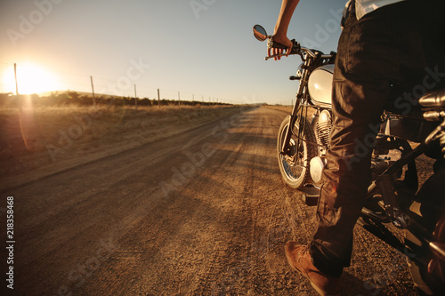 Rider standing on rural road with his bike