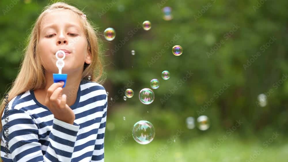 The nine-year-old girl plays with soap bubbles in the summer garden.
The nine-year-old girl plays with soap bubbles in the summer garden.