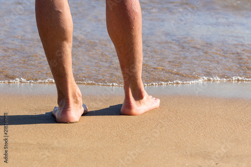 Male legs on a sandy beach
