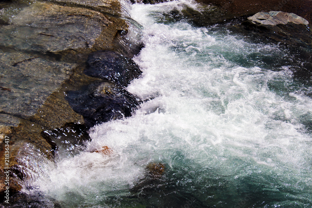 Water flowing white with foam in a mountain creek with stones Water flowing white with foam in a mountain creek with stones