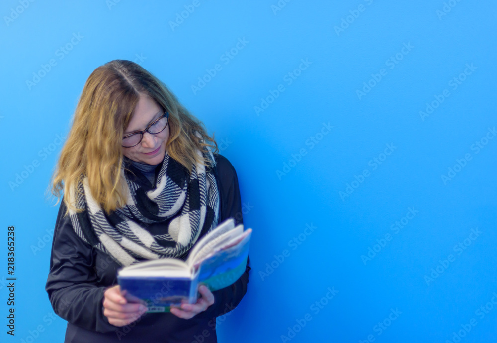 woman standing against wall reading book