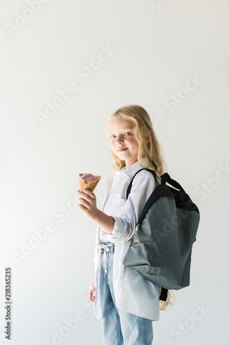 cute little child with backpack eating tasty ice cream isolated on white