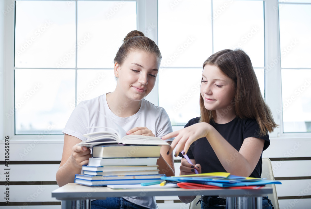Obraz premium Teenagers teens students are sitting at the table with books studying