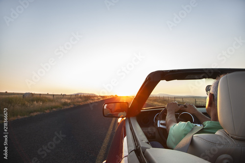 A senior Hispanic man at the wheel of his convertible sports car at sunset in eastern Washington State, USA. photo