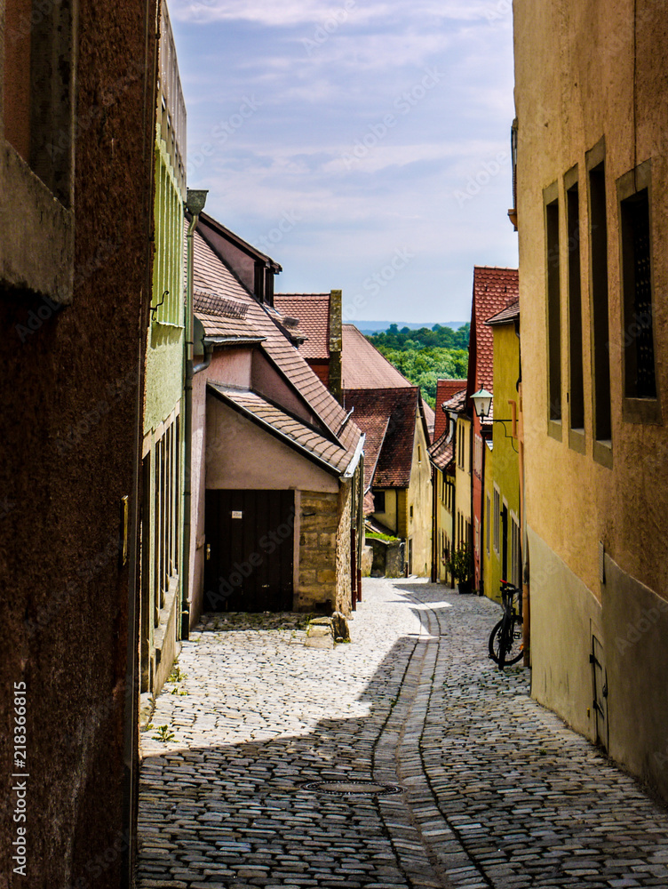 Fototapeta premium Scene from Rothenburg Ob Der Tauber, showing beautiful painted, timber framed, buildings along a narrow ally way. Taken on a cloudy day.