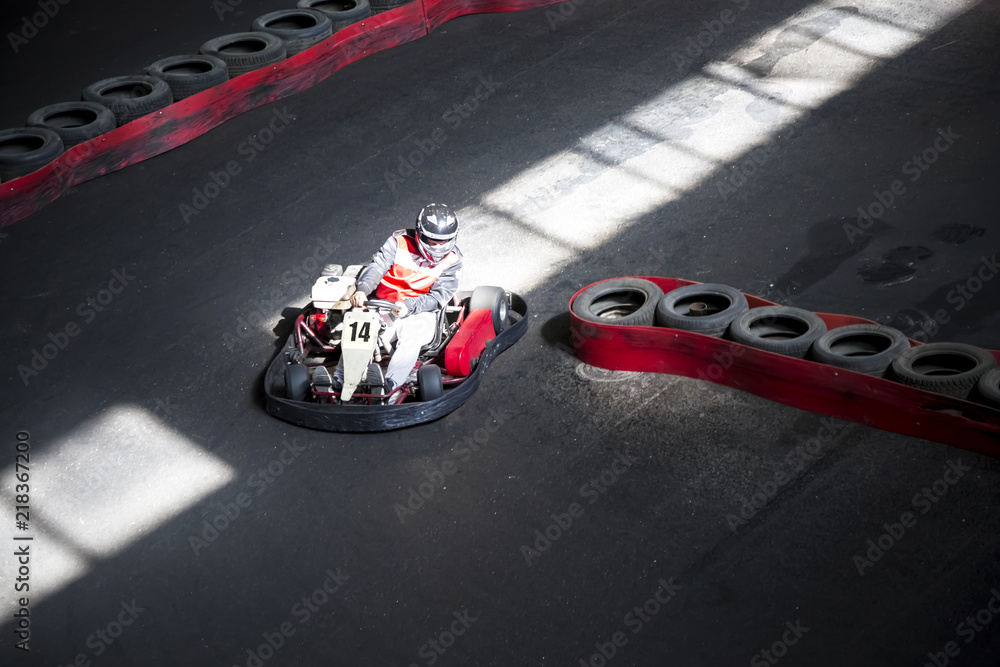 Riding on karting on the auto track. The young guy competes at the wheel of a carting.