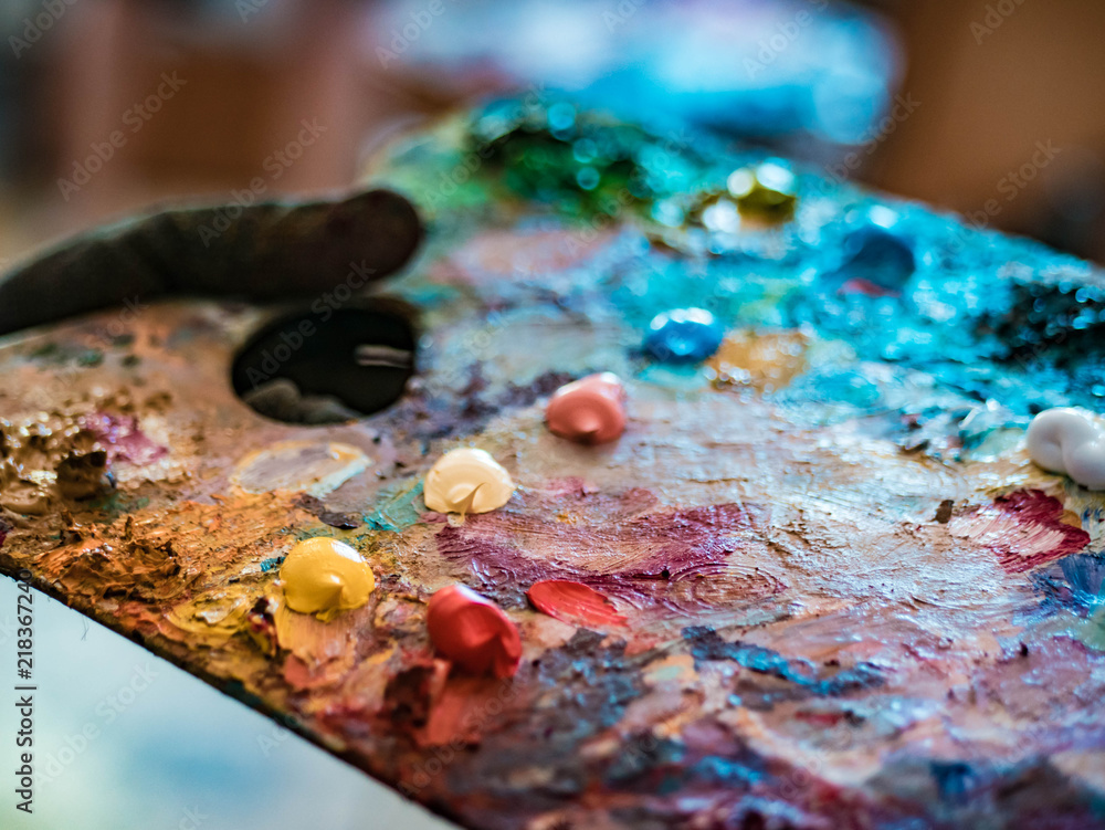 Wooden art palette with oil paints. Mixing colors together. Artistic instrument with many colors. Working tool with squeezed out tubes of paint. Wooden art palette with oil paints. Mixing colors together. Artistic instrument with many colors. Working tool with squeezed out tubes of paint.
