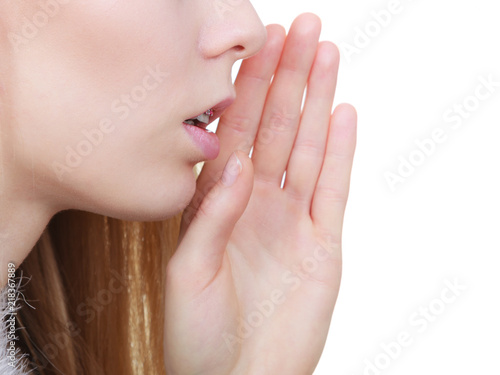 Young blonde woman whispering with hand near mouth
