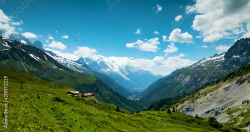 footage of the mont blanc massif near chamonix in the french alps showing clouds moving against blue summer sky and green alpine meadows