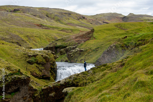 Island, Berglandschaft mit Fluß und Wasserfall, Frau genießt Ruhe in der Natur