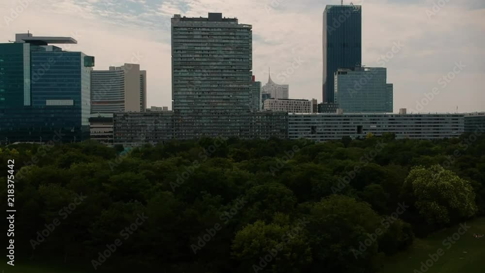 Donaucity skyline reveal shot behind green trees AERIAL Donaucity skyline reveal shot behind green trees AERIAL