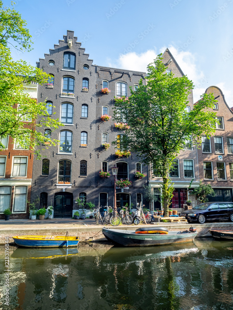 Amsterdam canal, bridge and typical houses, boats and bicycles during the day, Holland, Netherlands.