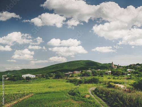 beautiful green fields, hills and cloudy sky near village in georgia © LIGHTFIELD STUDIOS