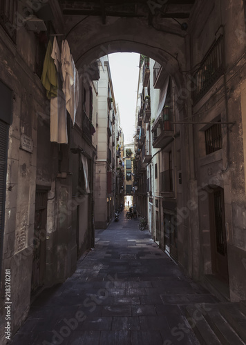 Narrow street in Gothic Quarter with hanging clothes on balcony on Barcelona, Spain © Moving Diary