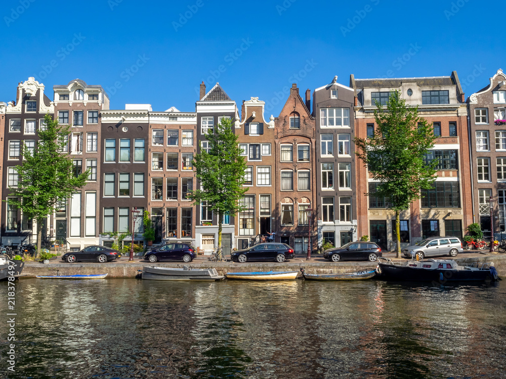 Amsterdam canal, bridge and typical houses, boats and bicycles during the day, Holland, Netherlands.