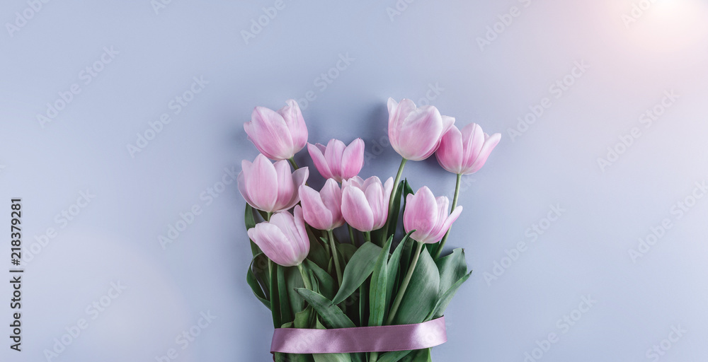Bouquet of pink tulips flowers on blue background. Waiting for spring. Greeting card or wedding invitation. Flat lay, top view
