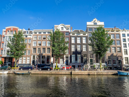 Amsterdam canal, bridge and typical houses, boats and bicycles during the day, Holland, Netherlands.