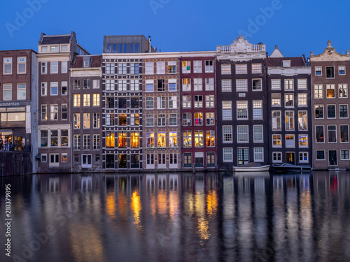 Historic buildings on the Damrak canal in the centre of beautiful Amsterdam at night.
