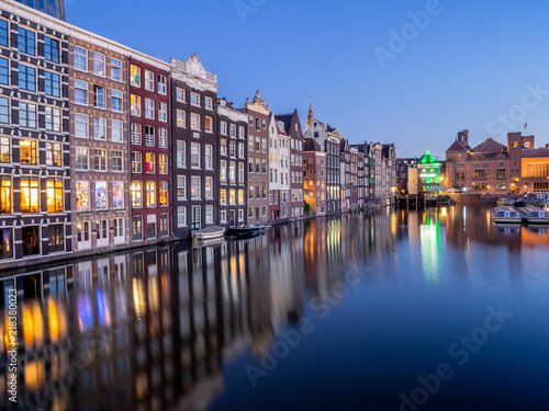 Historic buildings on the Damrak canal in the centre of beautiful Amsterdam at night.